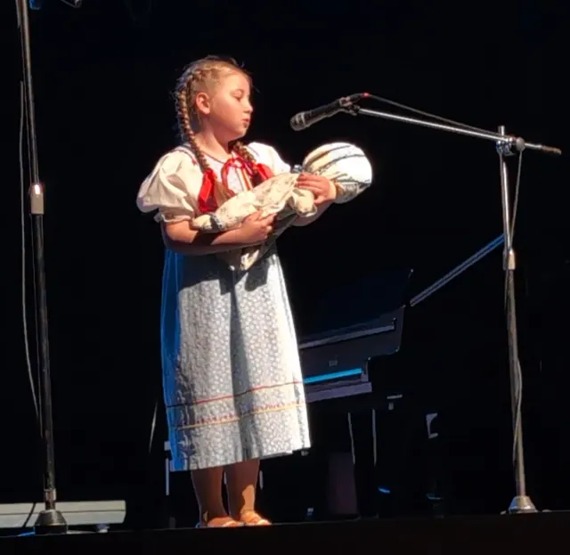 Mladá speváčka v ľudovom kroji pri mikrofóne
