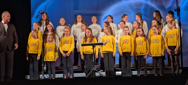 Detský zbor v žltých a bielych dresoch spieva na pódiu