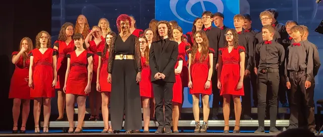 Mládežnícky zbor v červenom a tmavom, s dirigentkou a sólovým spevákom